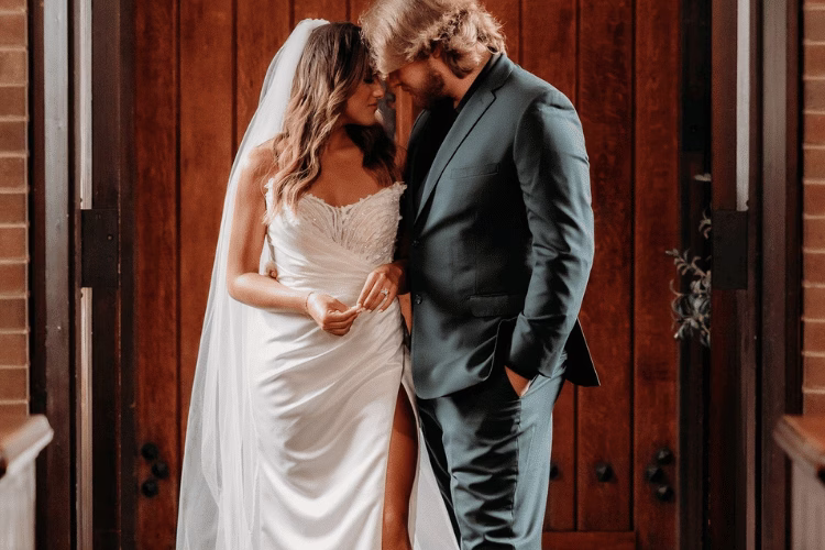 Bride and groom sharing a quiet moment together indoors, with the bride wearing a fitted wedding dress and veil while standing beside the groom in a dark suit.