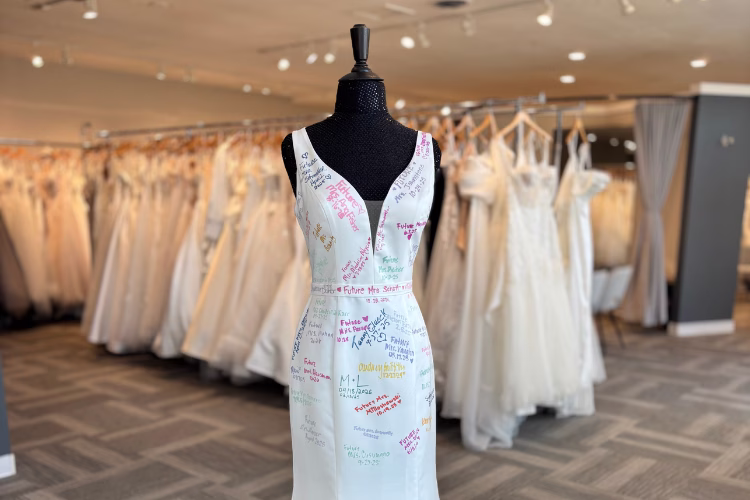 Signed bridal gown displayed in a bridal boutique surrounded by wedding dresses, celebrating brides and special memories.