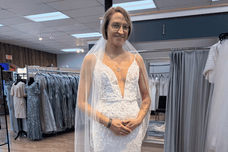 Bride wearing a beaded wedding dress and veil while standing inside a bridal boutique