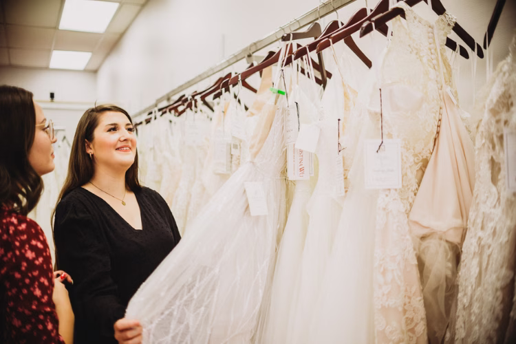 Bride looking at wedding dresses with a bridal consultant in a boutique