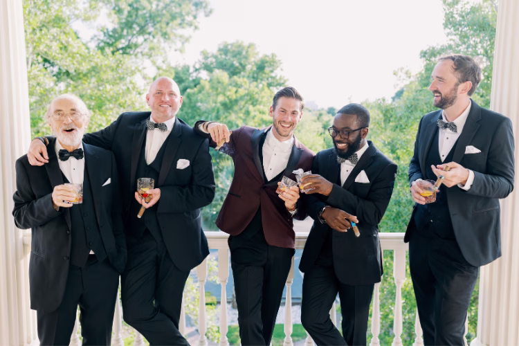 Men in tuxedos and suits celebrating together at a wedding